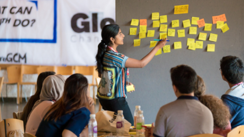 Person standing at a whiteboard in front of a group sitting at a table