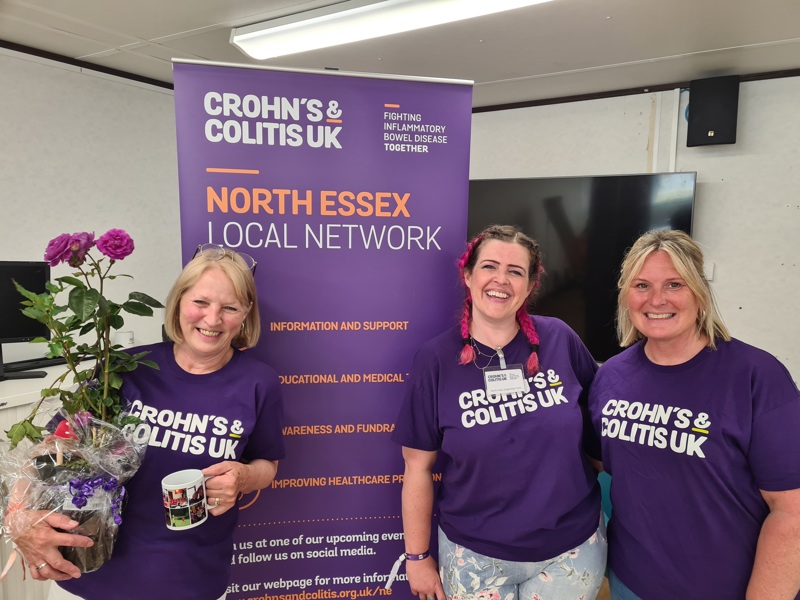 Three volunteers smiling in front of North Essex Local Network banner