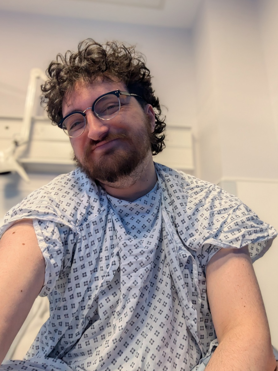 Tony wearing a hospital gown and smiling at the camera.