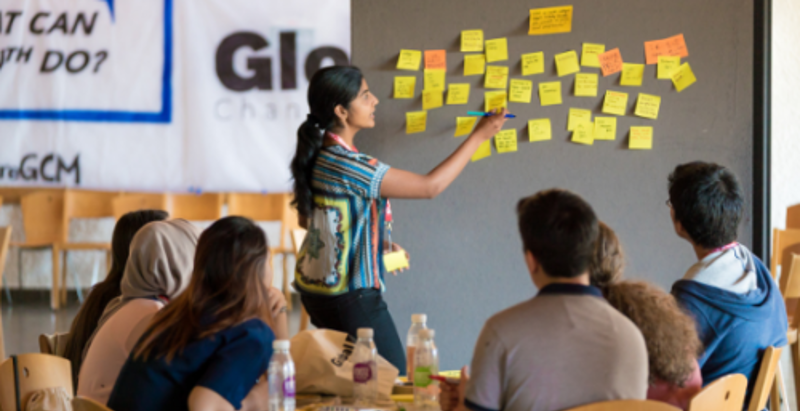 Person putting post-it notes on board in front of group