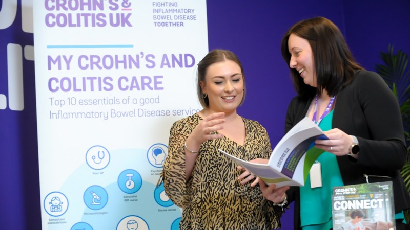 Two people talking and looking at a booklet. 