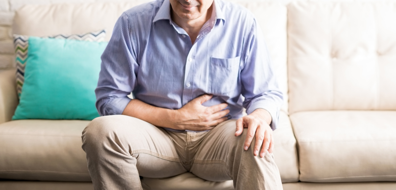Man sitting on a sofa holding his stomach