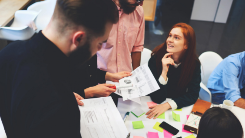 Group of people in a workshop talking around a table.
