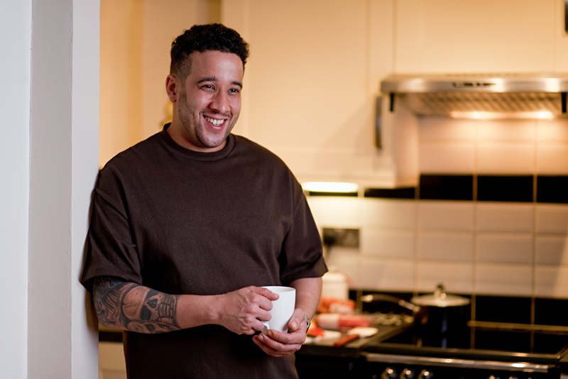 Man in kitchen at home with a mug of tea